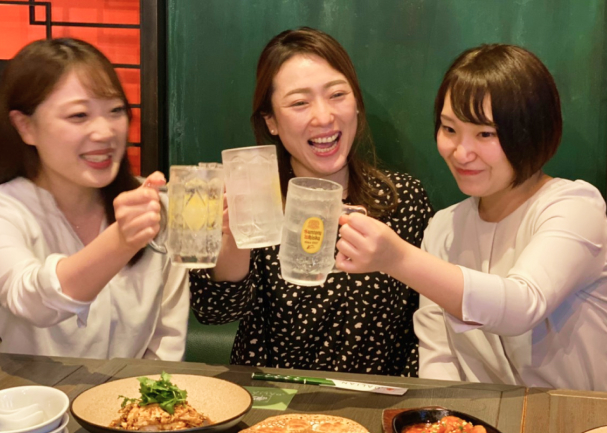 アジアンテイブルの料理を囲み笑顔で乾杯する女性たち